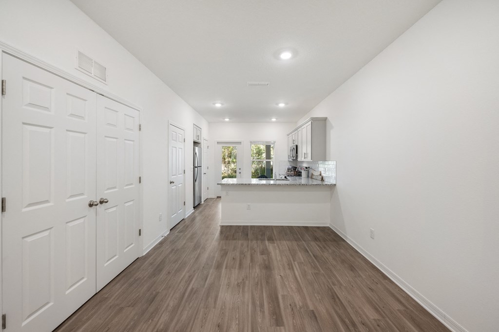 A long hallway with white walls and wood flooring.