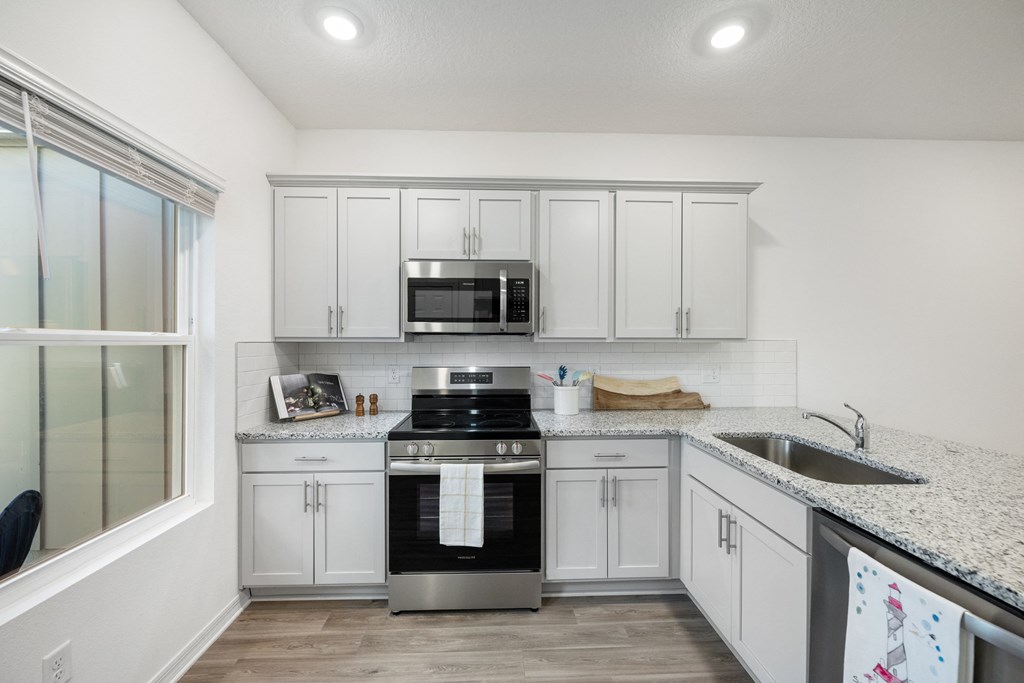 A kitchen with white cabinets and a granite countertop.