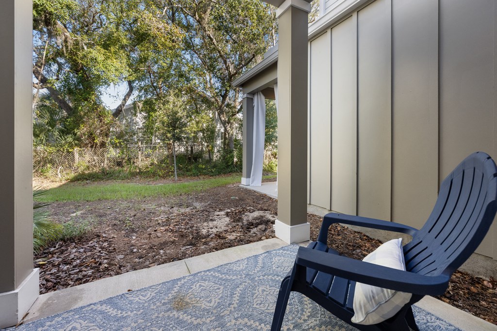 A blue chair with a white pillow is on a porch.