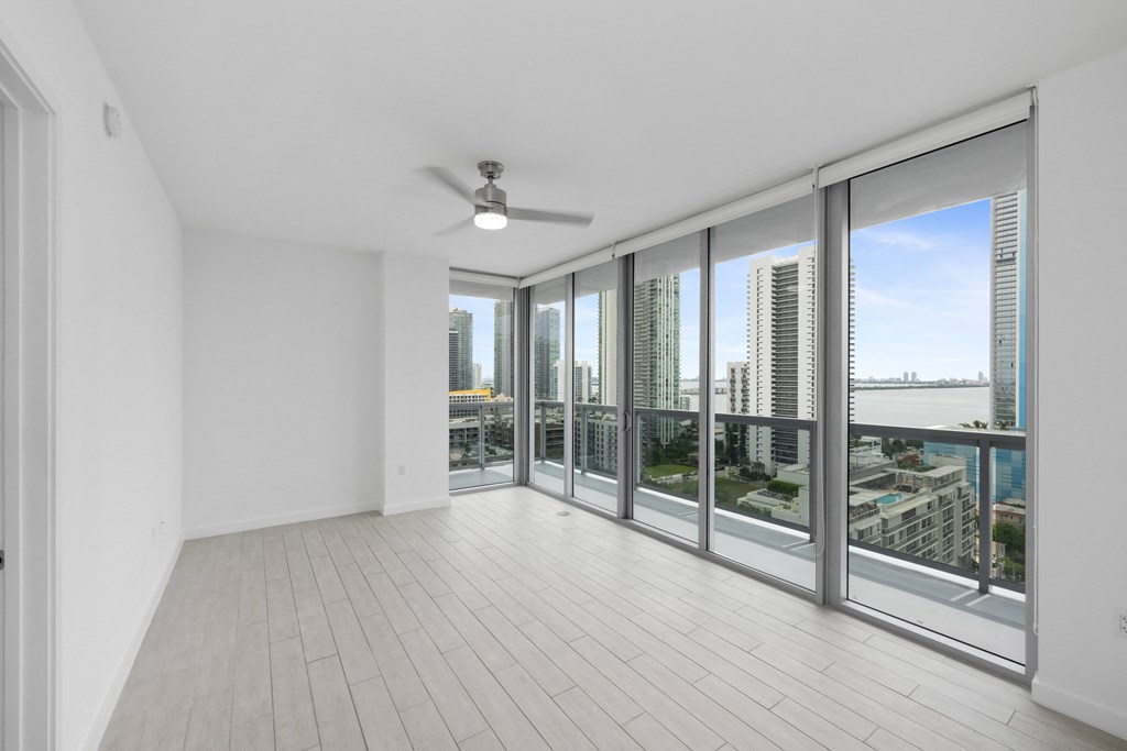 an empty living room with a ceiling fan and a view of the city