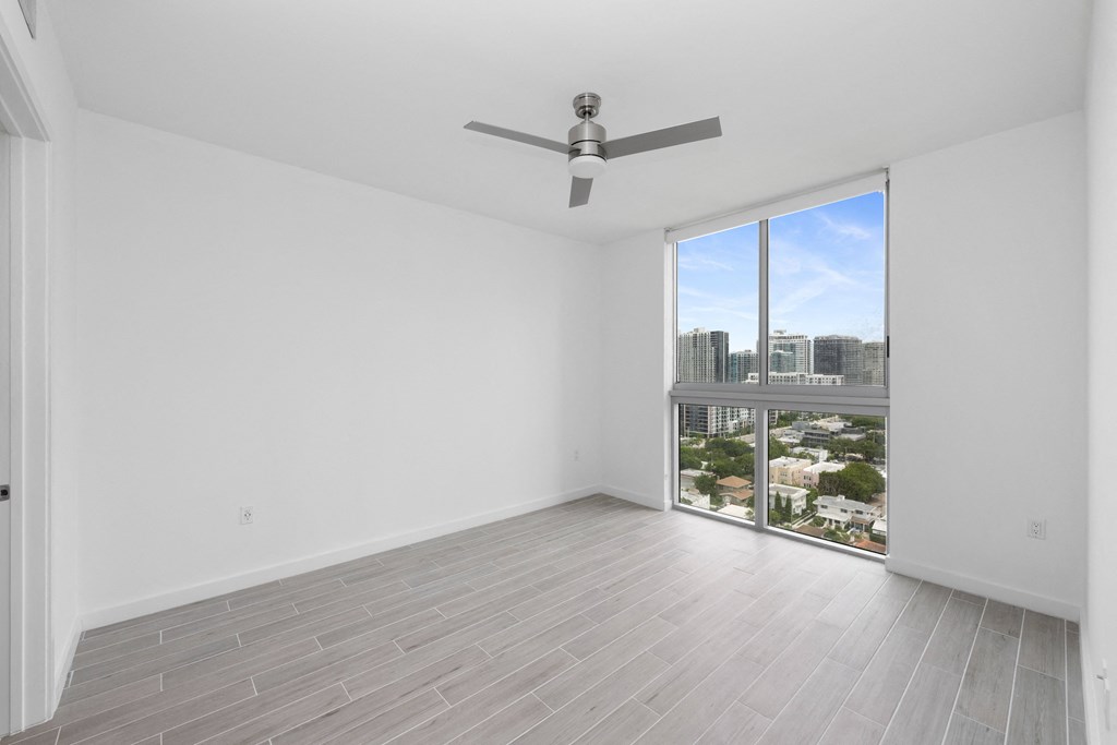 a bedroom with a large window and a ceiling fan
