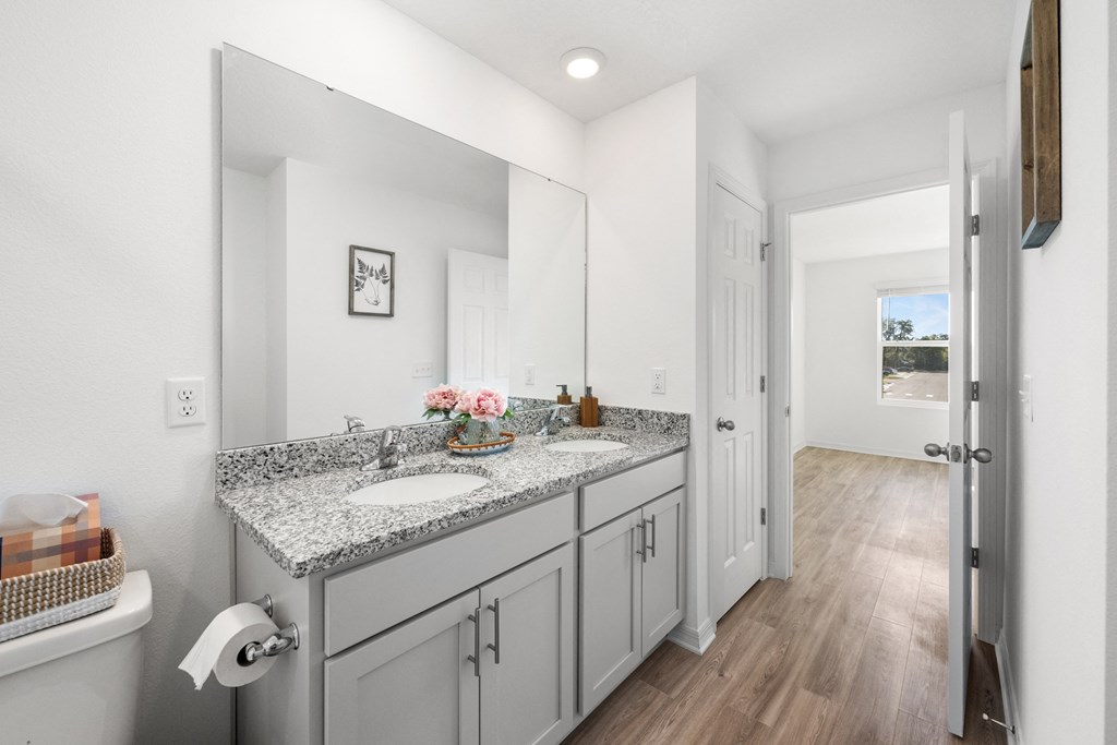A bathroom with a granite countertop and white cabinets.