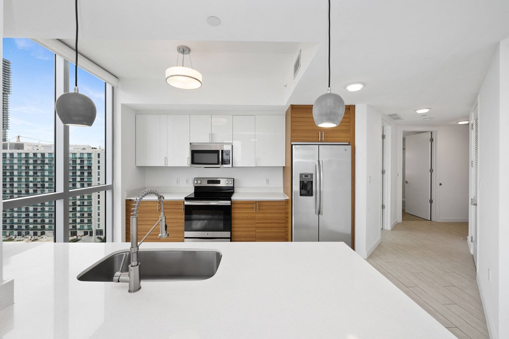 a kitchen with white countertops and a large window