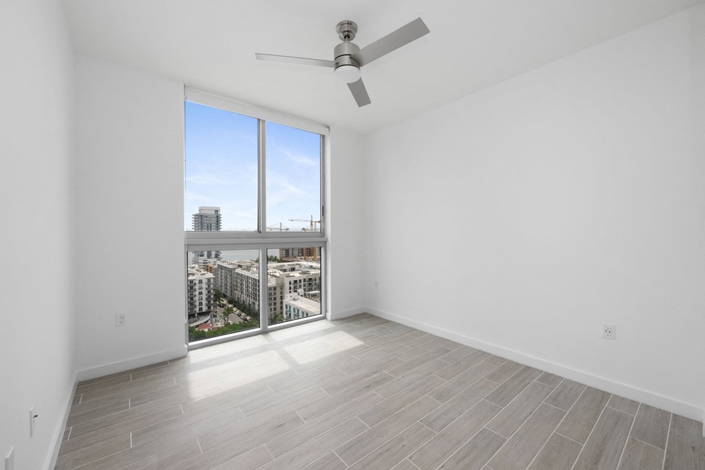 a bedroom with a large window and a ceiling fan