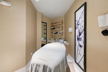 A spa room with a white bed and a large framed picture on the wall.