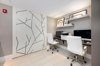 A white chair is in front of a desk with a computer monitor and printer.