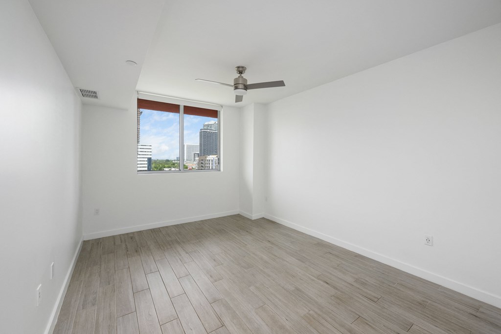 a bedroom with hardwood floors and a large window