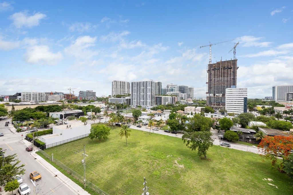 an aerial view of a grassy area with a tall building under construction in the background