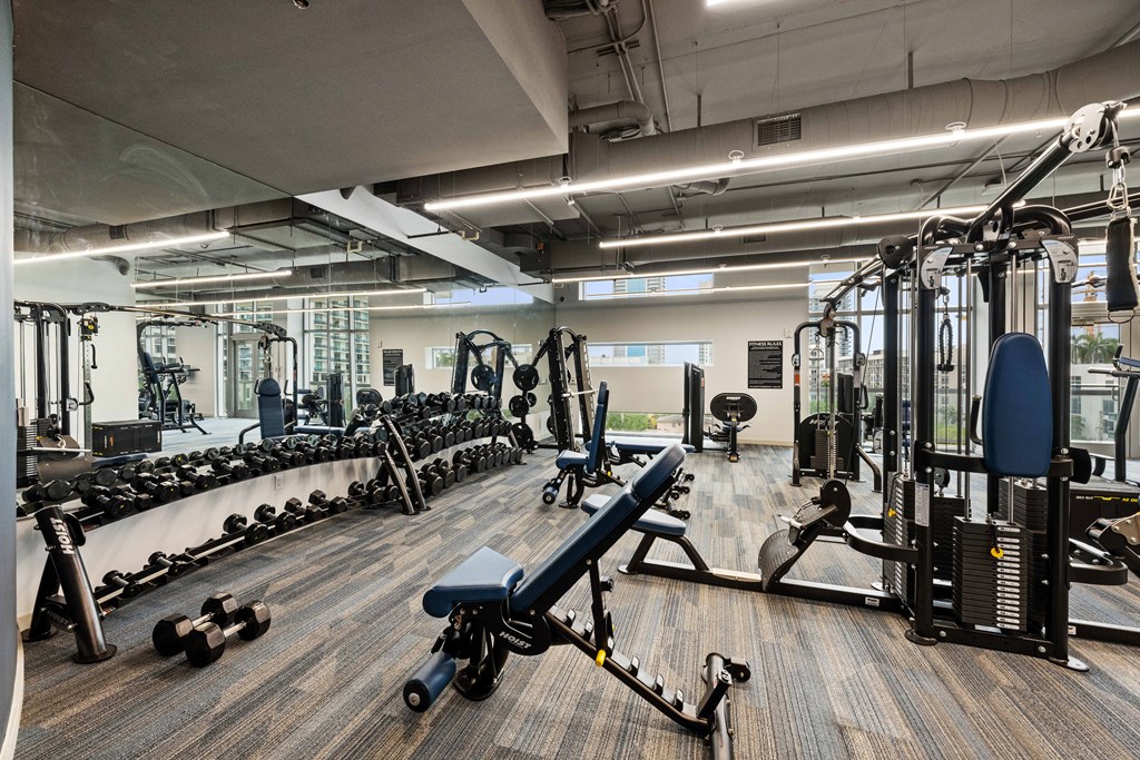 a spacious fitness center with cardio equipment and weights