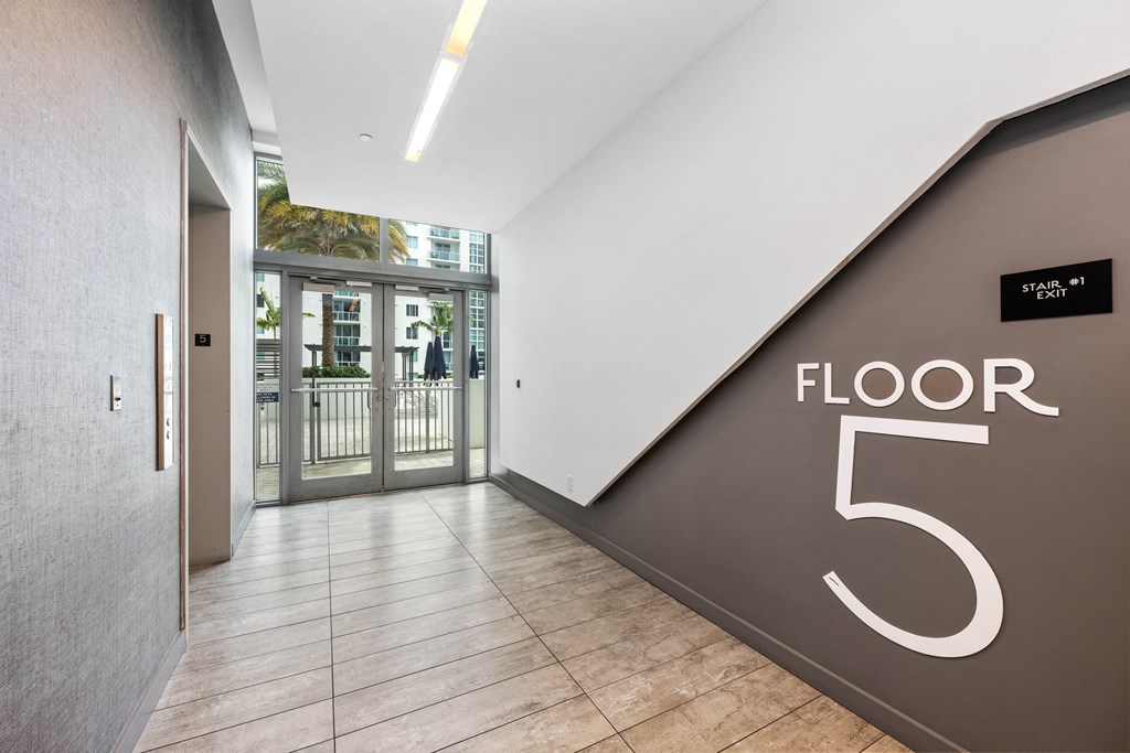 a large hallway with a large floor number on the wall and a glass door in the background