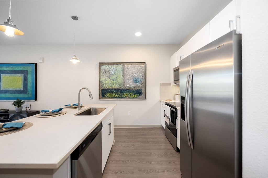 a kitchen with white countertops and stainless steel appliances
