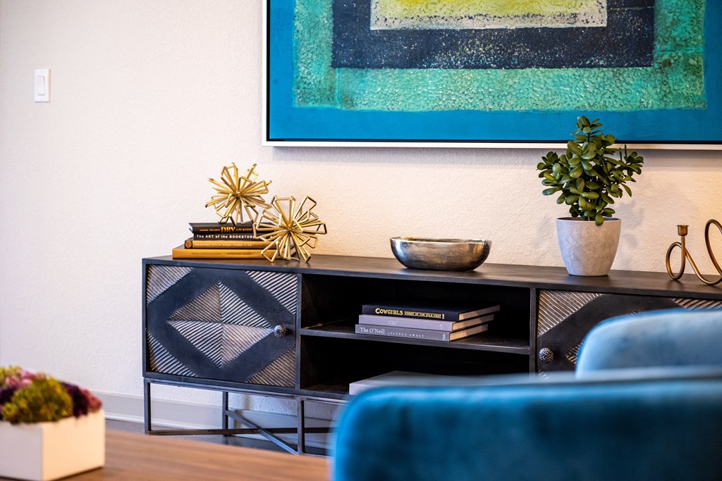 living room with a blue couch and a black credenza with books and decorations on top
