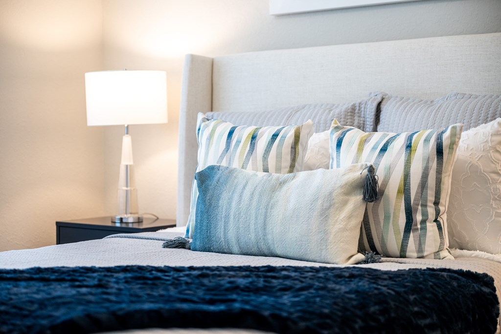 bed with pillows and a nightstand with a lamp