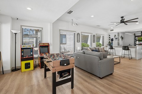 A living room with a grey couch, a wooden coffee table, and a yellow arcade machine.
