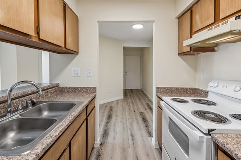 A kitchen with wooden cabinets and a white stove top oven.