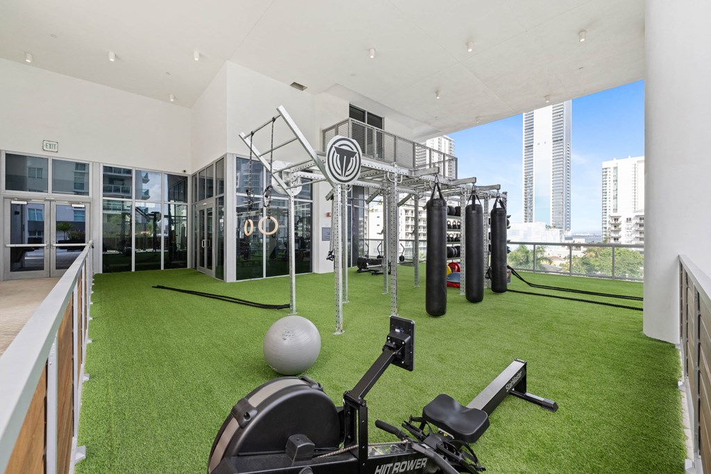 a gym with grass and weights on the floor and a view of the city