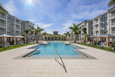 A large swimming pool in the middle of a resort surrounded by palm trees.