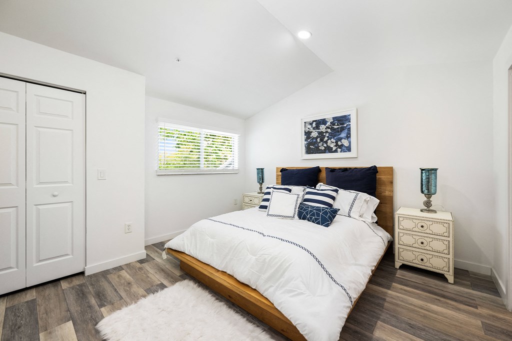 a bedroom with white walls and a bed with blue and white pillows
