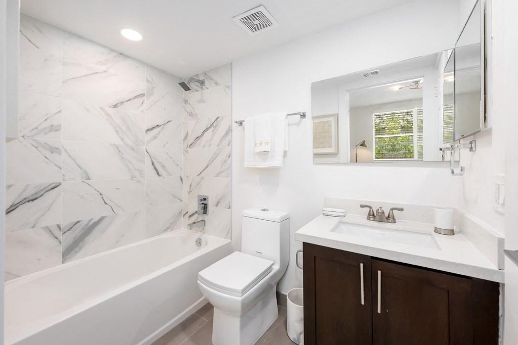 a bathroom with a tub sink toilet and a mirror