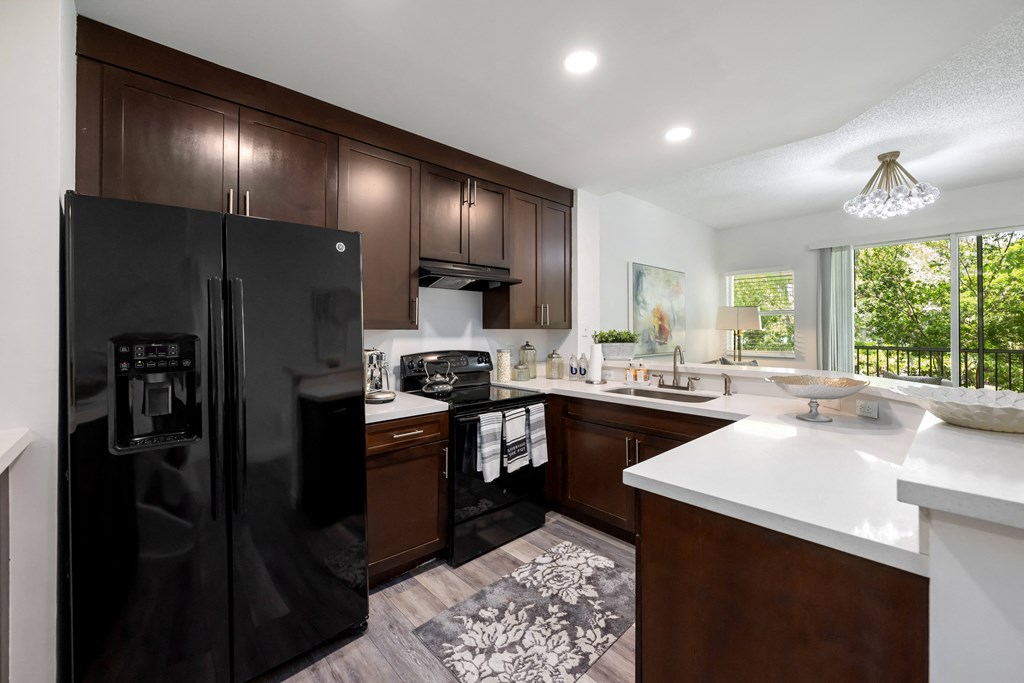 a kitchen with dark wood cabinets and white counter tops and a black refrigerator