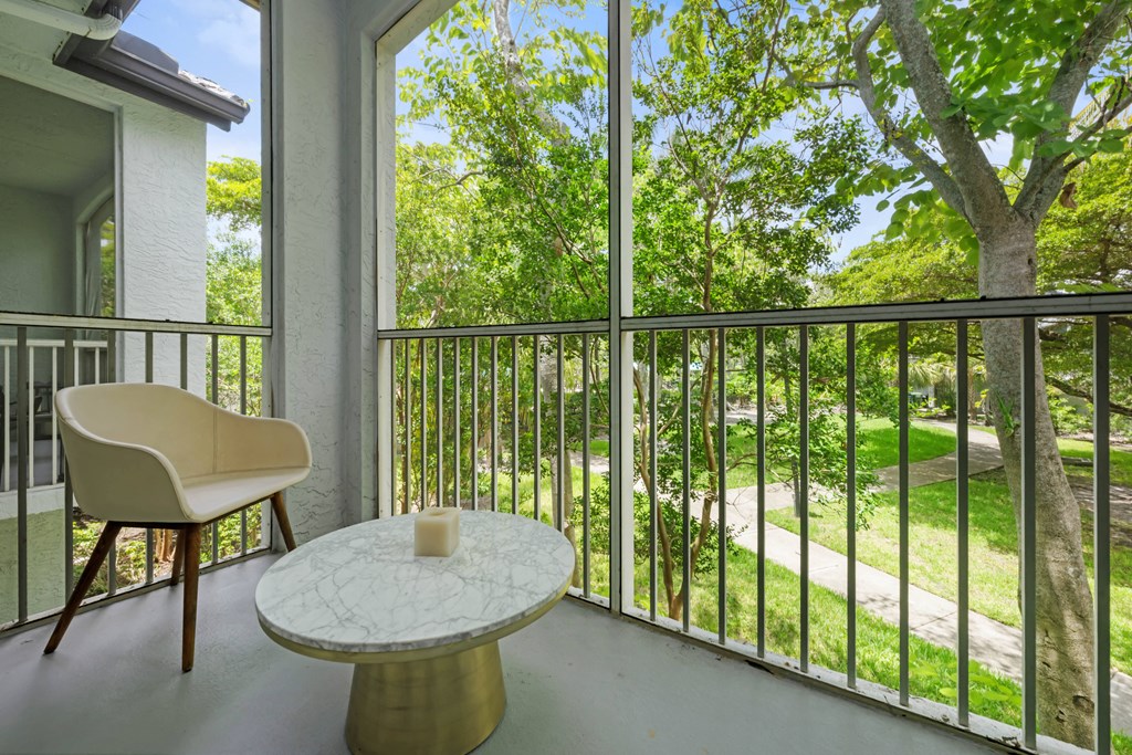 a balcony with a table and a chair and a view of trees