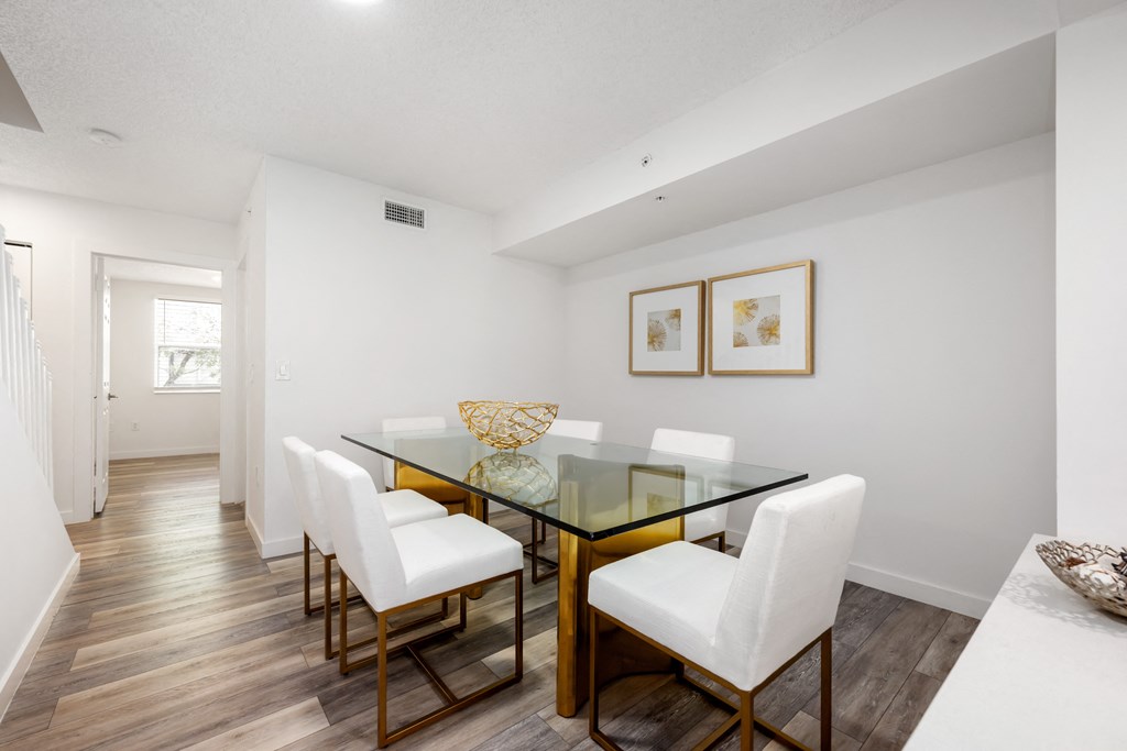 a dining room with a glass table and white chairs