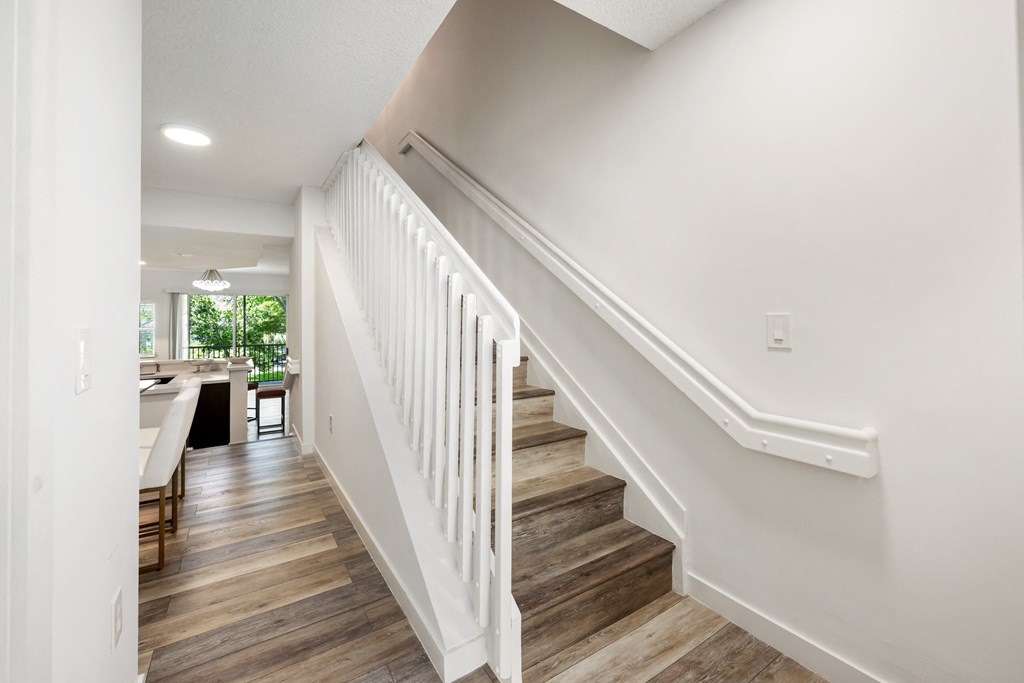 an image of a staircase in a home with wood floors and white railings