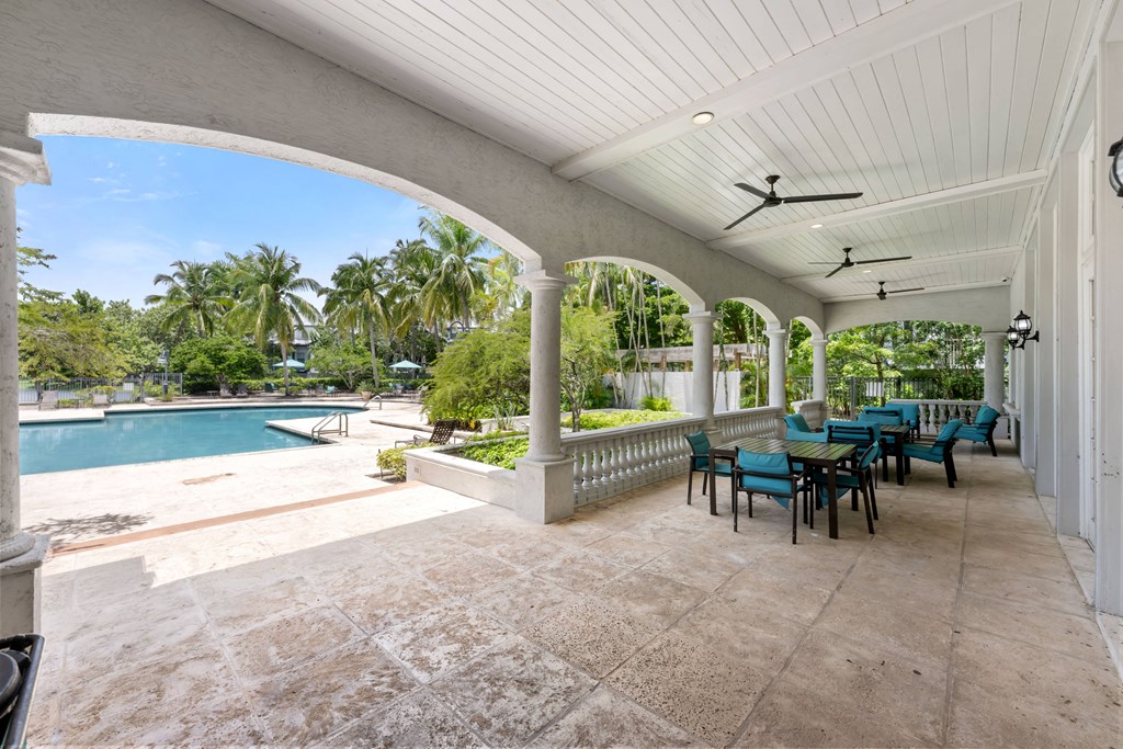a covered patio with a table and chairs next to a swimming pool