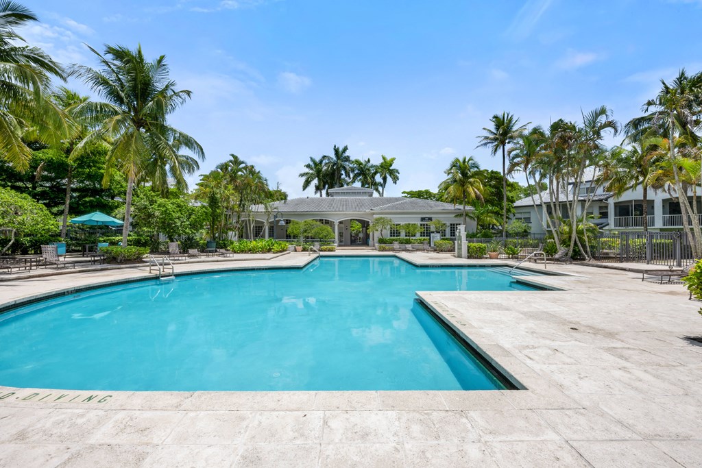 a swimming pool with palm trees and a building in the background