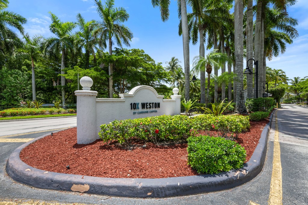 the sign at the front of the 100 west entrance to the community with palm trees