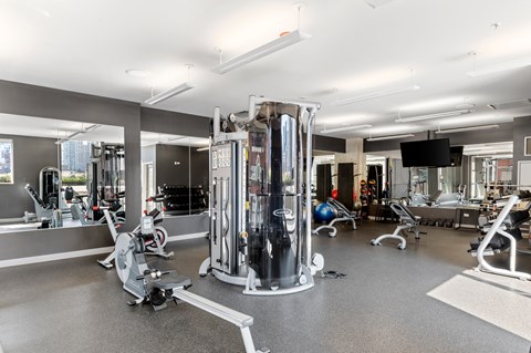 A gym with a variety of equipment including a treadmill, weights, and a television.