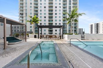 a pool and hot tub in front of a tall building