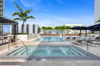 a resort style pool with chaise lounge chairs and palm trees in the background