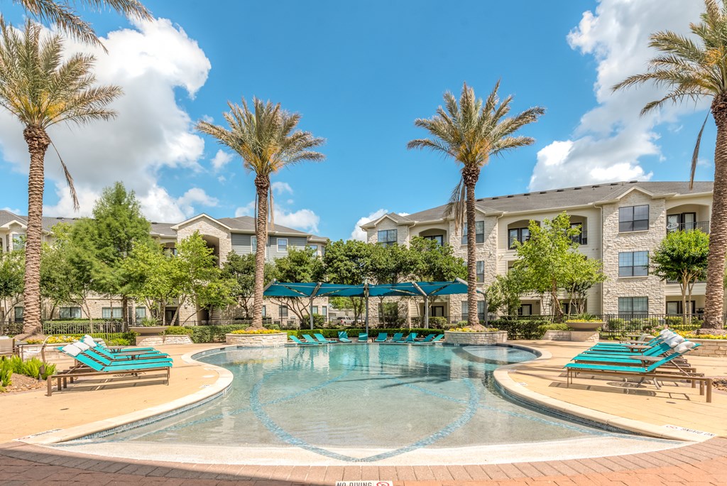 A swimming pool surrounded by palm trees and lounge chairs.