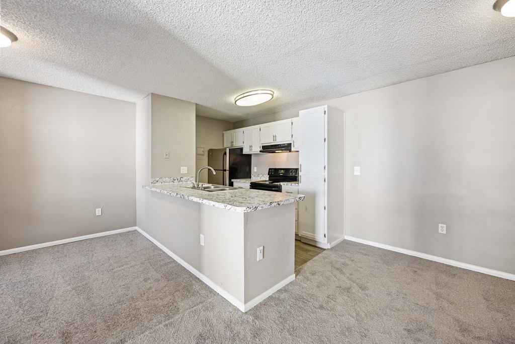 an empty living room and kitchen with a granite counter top