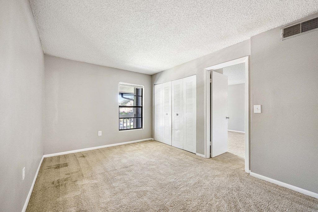 a spacious living room with carpet and a door to a bedroom