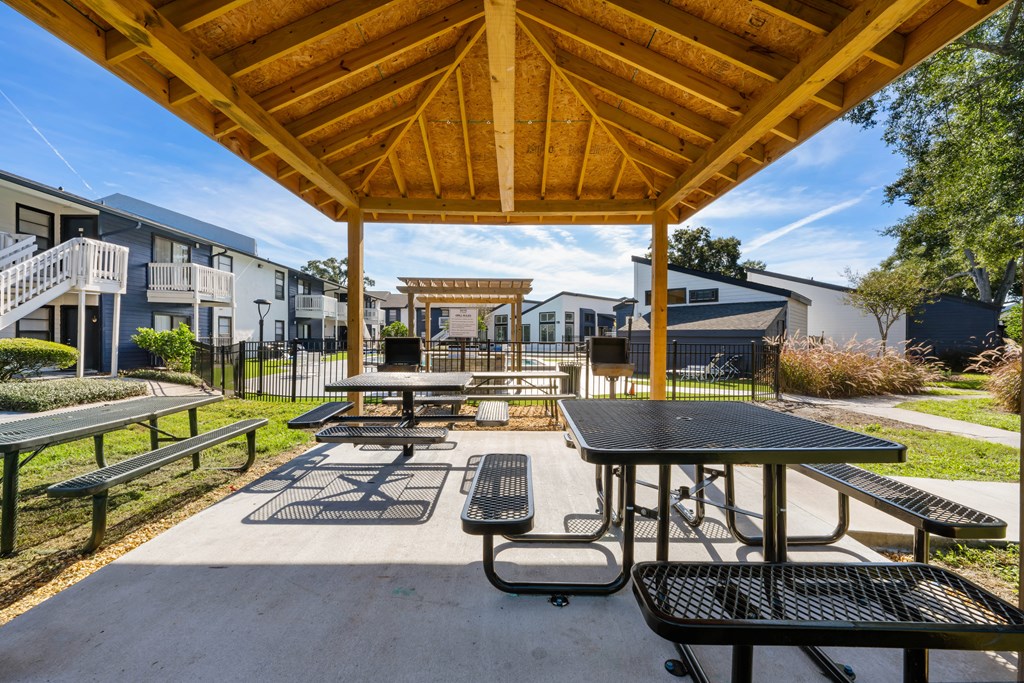 two picnic tables and benches under a pavilion at an apartment complex