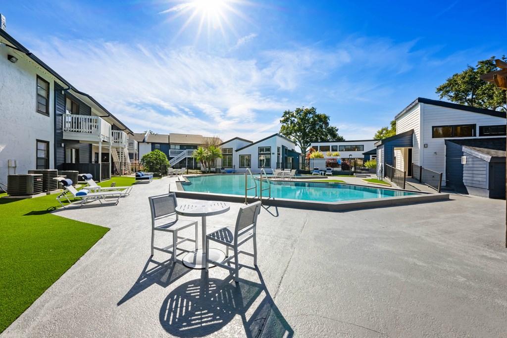 a pool with chairs and a table in front of a building