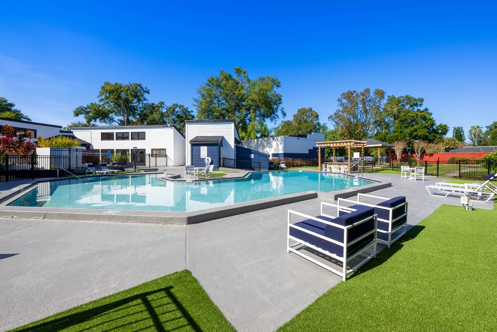 a resort style pool with lounge chairs and tables around it