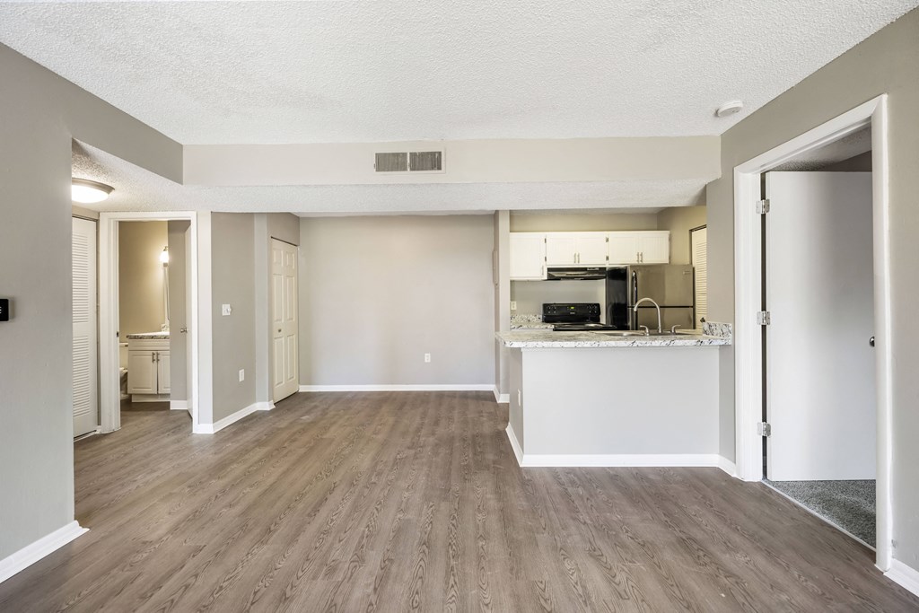 the spacious living room and kitchen of an apartment