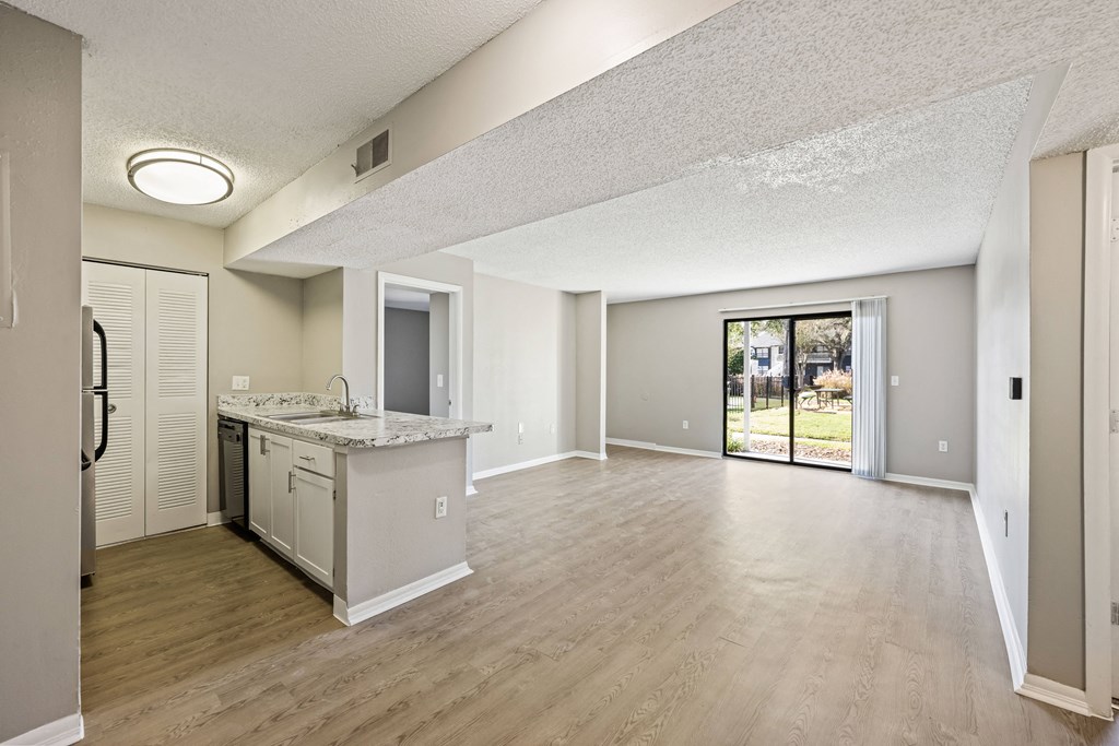 an empty living room and kitchen with a door to the yard