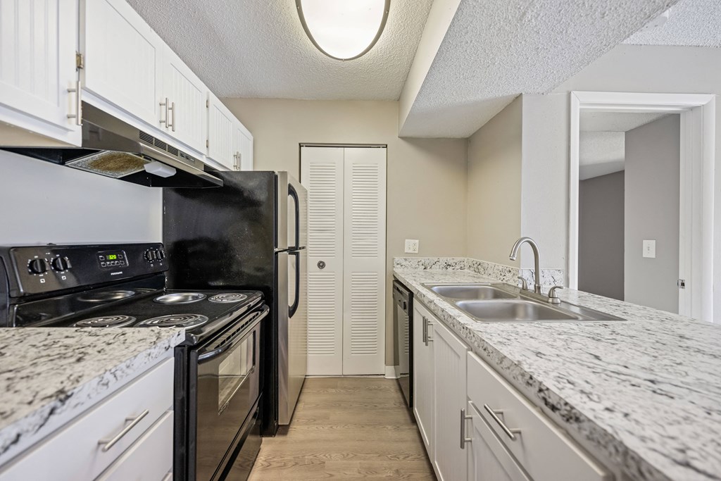 a kitchen with granite counter tops and black appliances and white cabinets