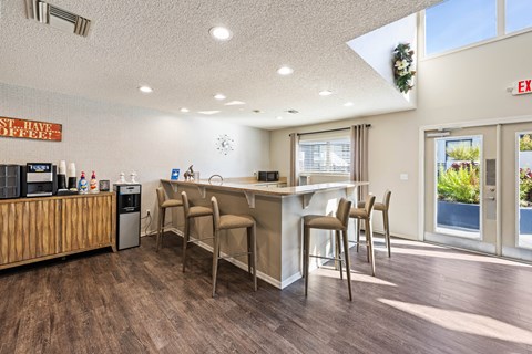 a kitchen with a bar and chairs in front of a window