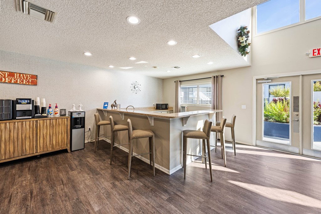 a kitchen with a bar and chairs in front of a window