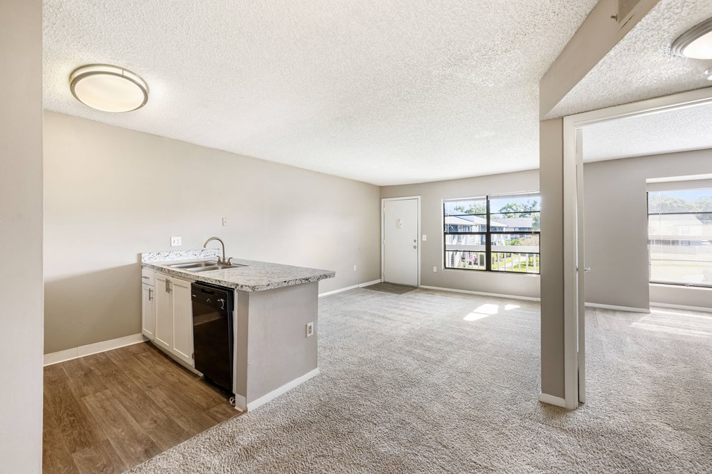 an empty living room and kitchen with a large window
