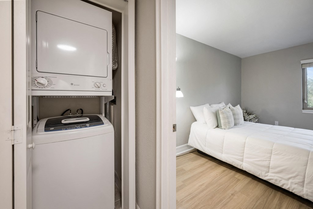 a small bedroom with a bed and a washer and dryer in a room