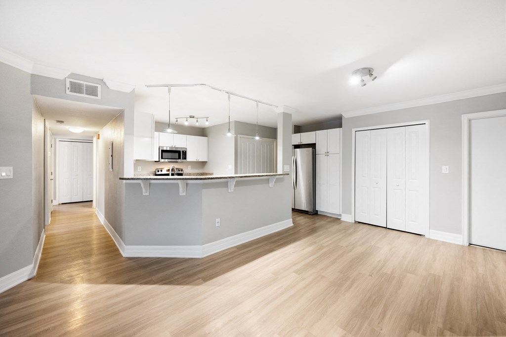an empty living room and kitchen with white walls and wood floors