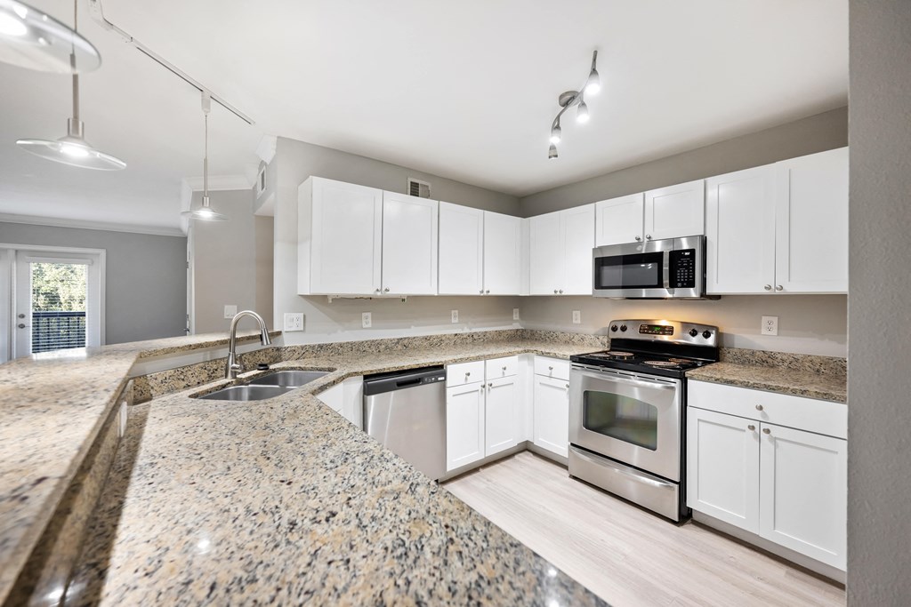 an empty kitchen with granite counter tops and white cabinets
