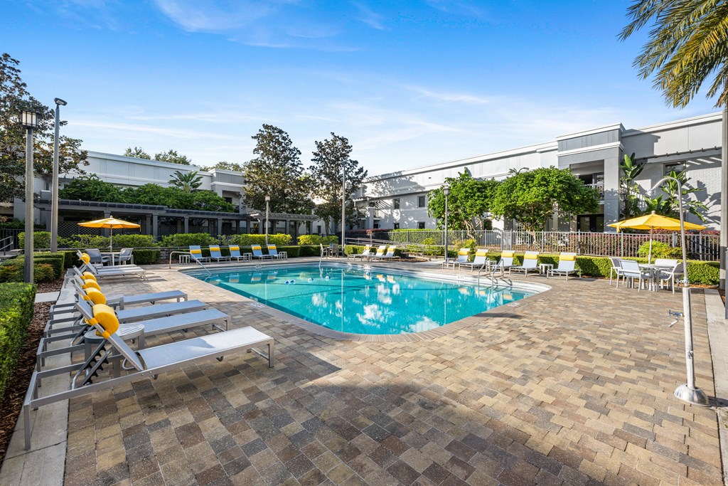 a swimming pool with lounge chairs and a building in the background