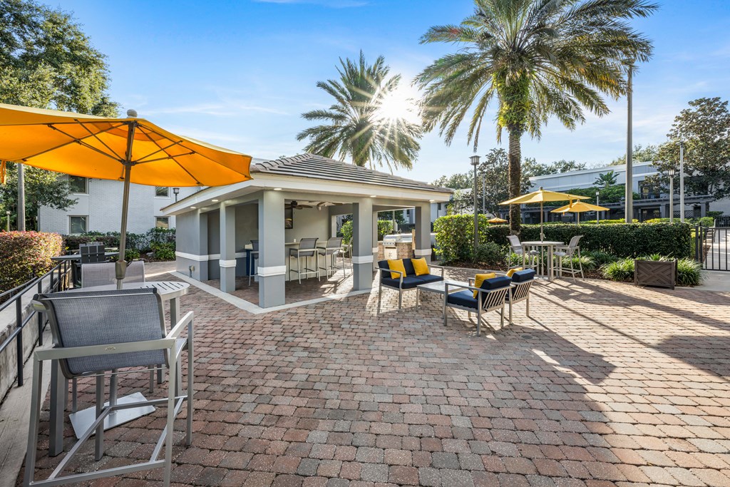 a patio with chairs and umbrellas and a house